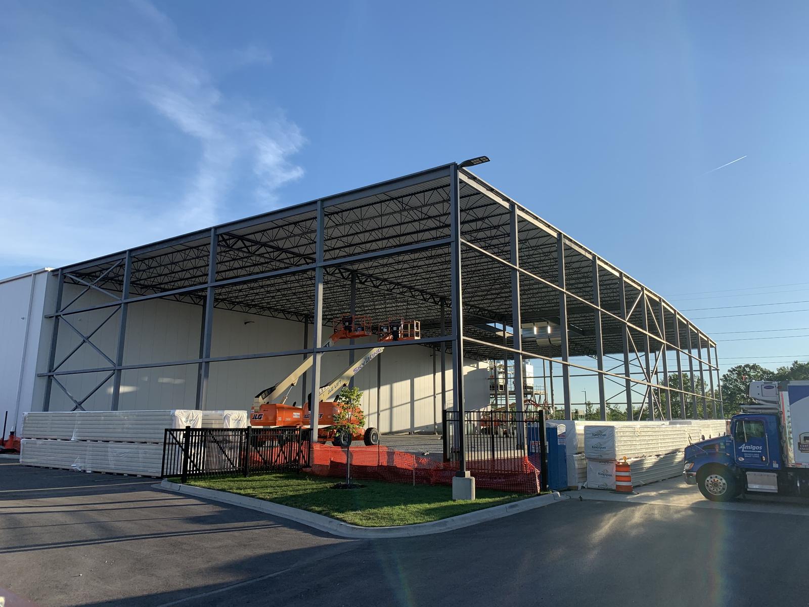 Structural steel frame and roof deck of the freezer addition partly clad in insulated metal panel, built directly against the existing plant