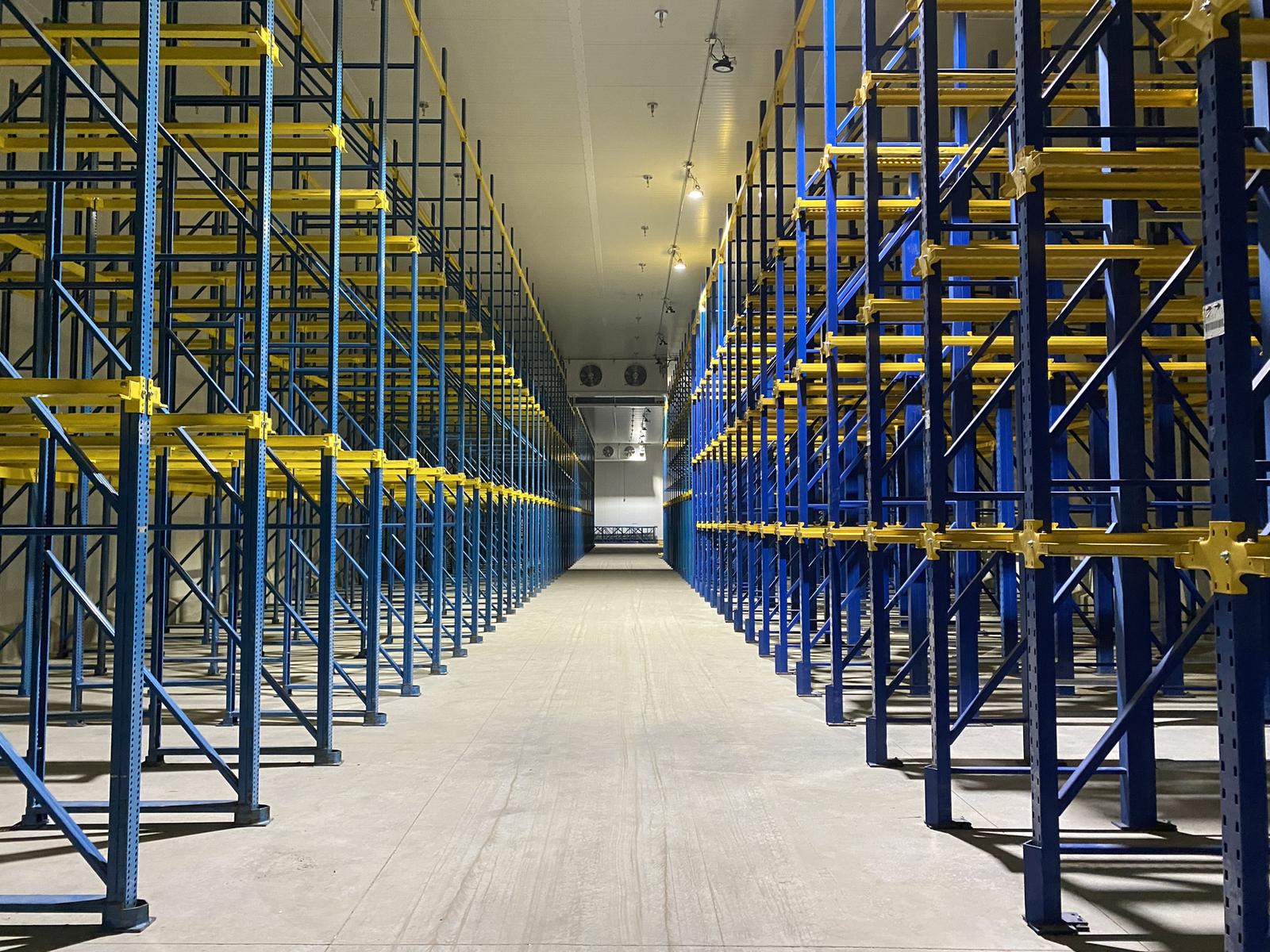 Pallet racking installed in the renovated cold storage area, with insulated metal panel walls and an evaporator at the far end