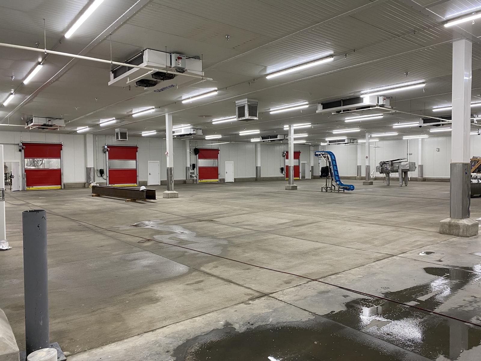 Renovated production room with insulated metal panel walls and ceiling, ceiling-mounted refrigeration units, and insulated high-speed roll-up doors