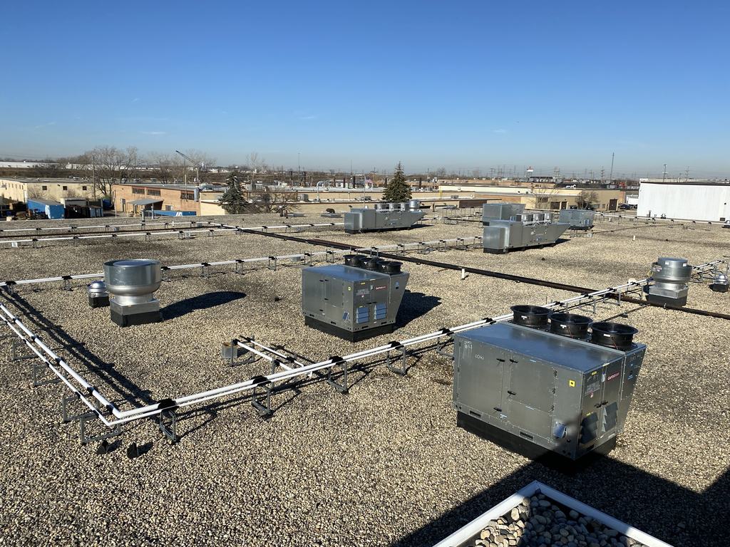 Rooftop mechanical units and piping runs installed on the roof of the facility