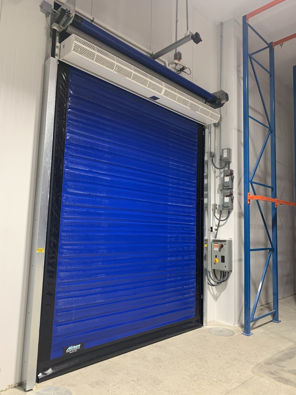 Blue insulated high-speed roll-up door set into the wall of a new temperature-controlled bay
