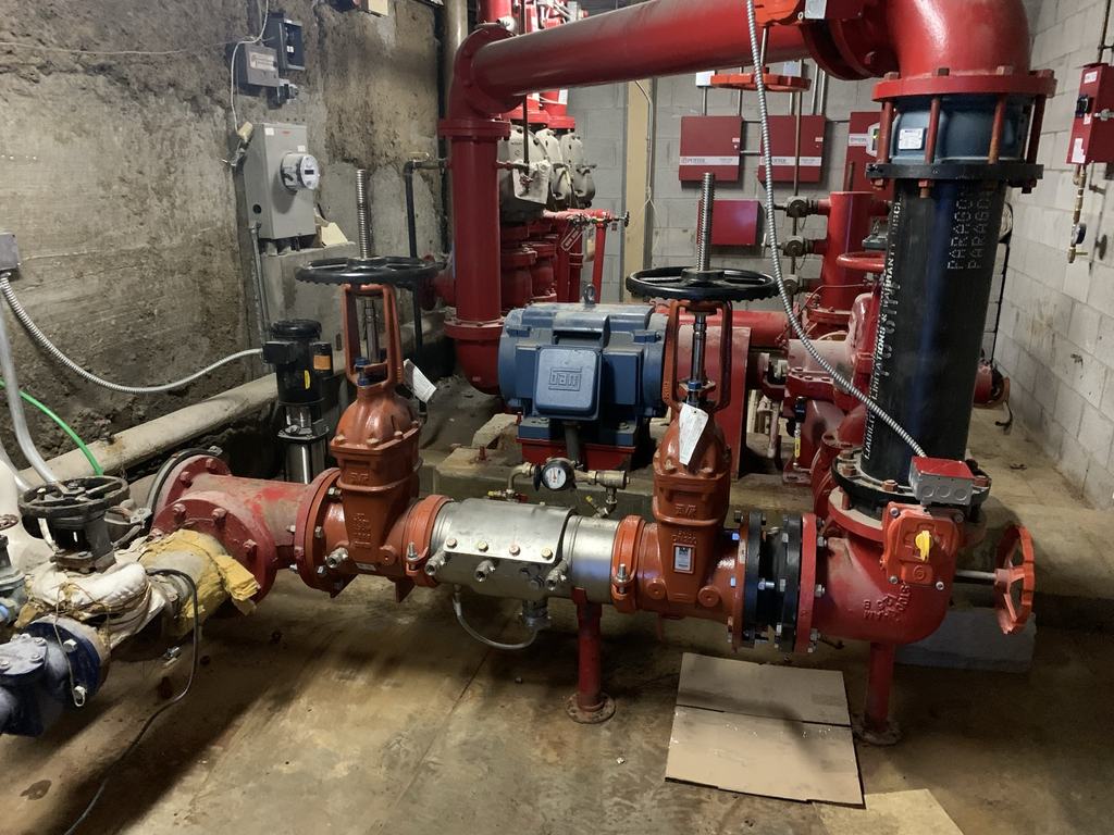 Fire protection service assembly with backflow preventer and gate valves installed in the building's riser room