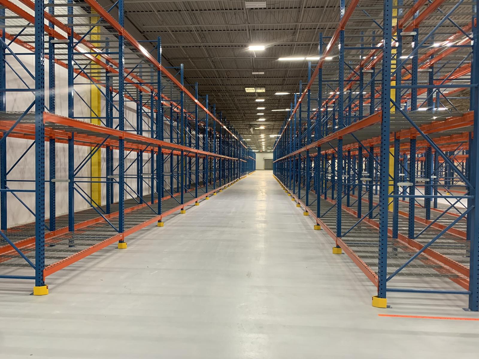 Long aisle of blue and orange pallet racking running the length of a completed storage bay