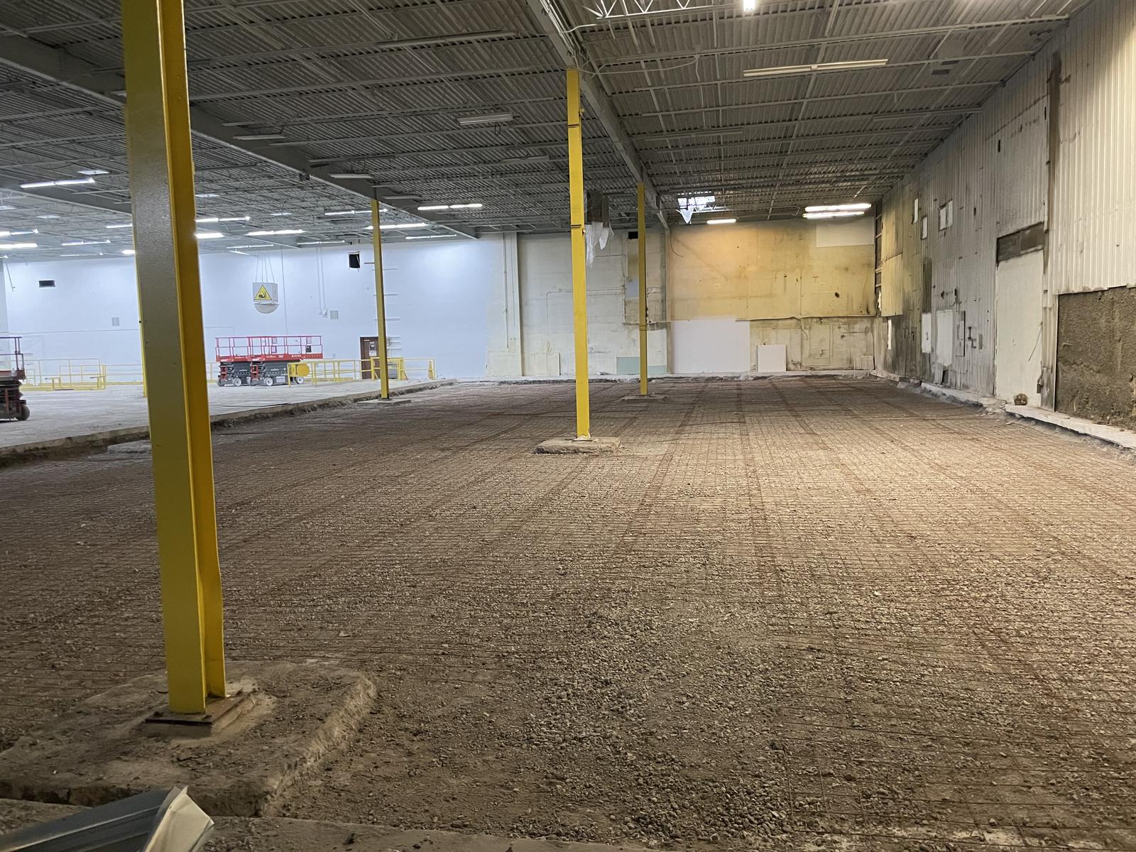 Warehouse interior stripped back to a stone base across the full width of the bay, with columns left standing